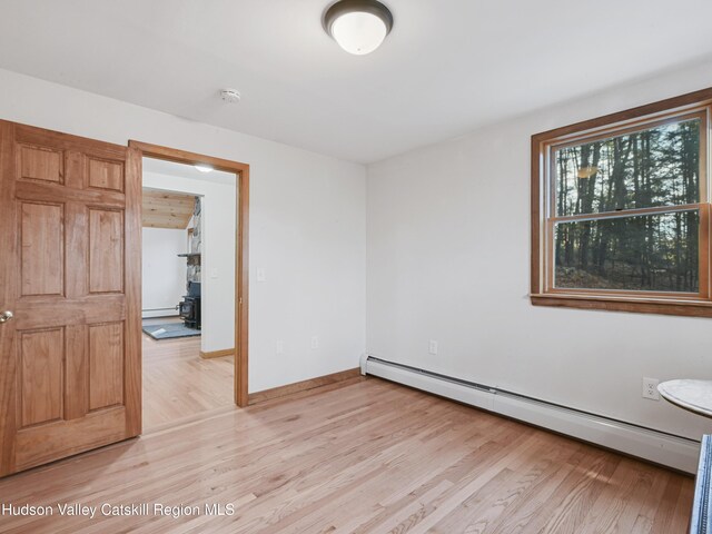 unfurnished room with light hardwood / wood-style floors and a baseboard heating unit