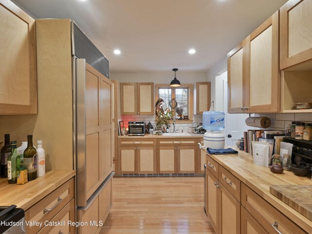 kitchen with light brown cabinets, light wood-type flooring, and hanging light fixtures