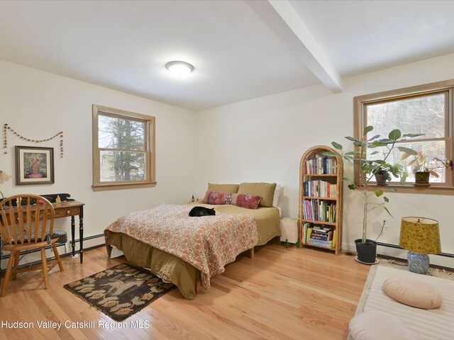 bedroom featuring beam ceiling, multiple windows, wood-type flooring, and a baseboard radiator