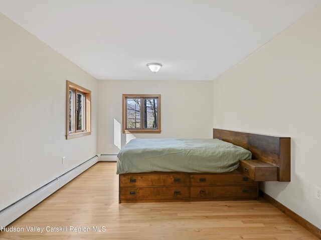 bedroom with a baseboard radiator and light wood-type flooring