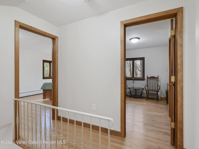 corridor with plenty of natural light, a baseboard heating unit, and light hardwood / wood-style flooring