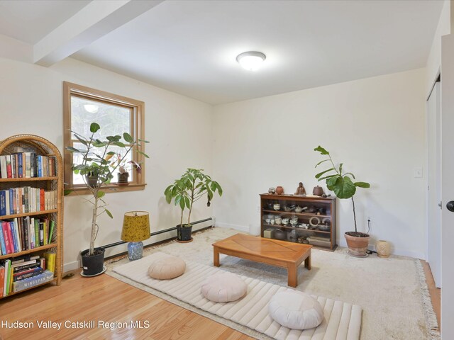 sitting room featuring hardwood / wood-style flooring, baseboard heating, and beamed ceiling