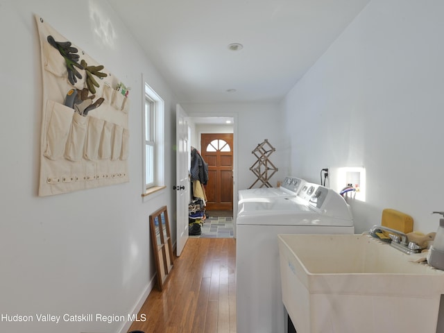 washroom with separate washer and dryer, sink, and wood-type flooring