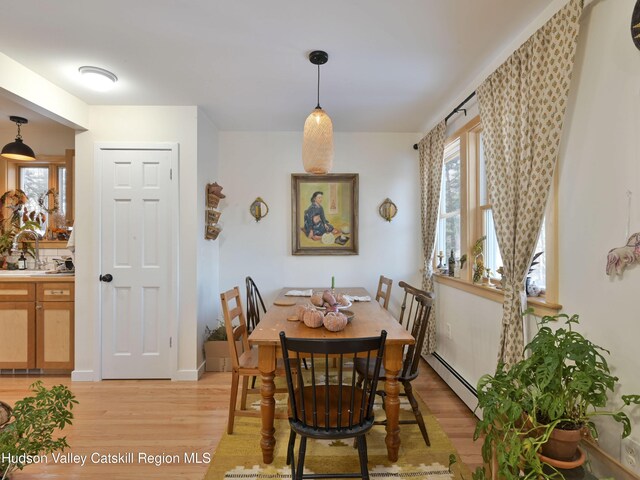 dining area featuring light wood-type flooring, baseboard heating, and sink