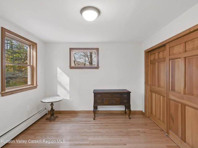 living area with light wood-type flooring and a baseboard heating unit