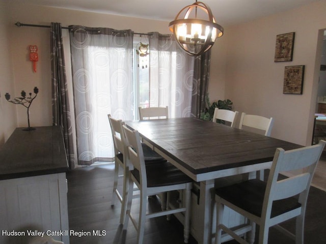 dining space featuring dark wood-type flooring and a notable chandelier