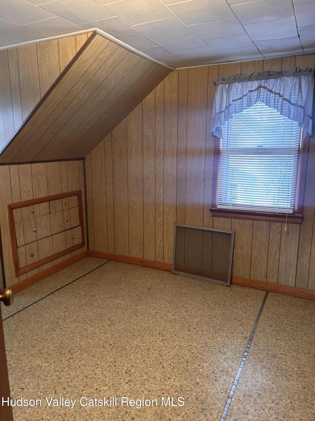 additional living space with wooden walls and vaulted ceiling