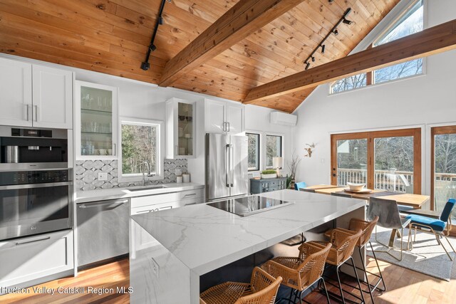 kitchen featuring stainless steel appliances, a center island, light stone countertops, and white cabinets