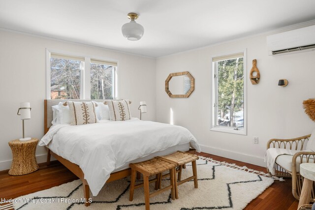 bedroom featuring hardwood / wood-style flooring, ornamental molding, a wall mounted air conditioner, and multiple windows