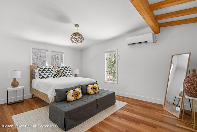 bedroom with beamed ceiling, a wall mounted air conditioner, and light hardwood / wood-style floors