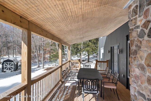 snow covered deck with a shed