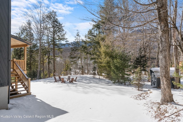 yard covered in snow with a storage unit and an outdoor fire pit