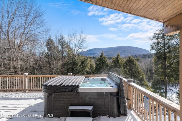 snow covered deck with a hot tub and a mountain view