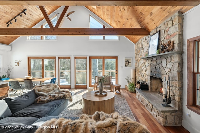 living room with a fireplace, rail lighting, vaulted ceiling with beams, wood ceiling, and light wood-type flooring