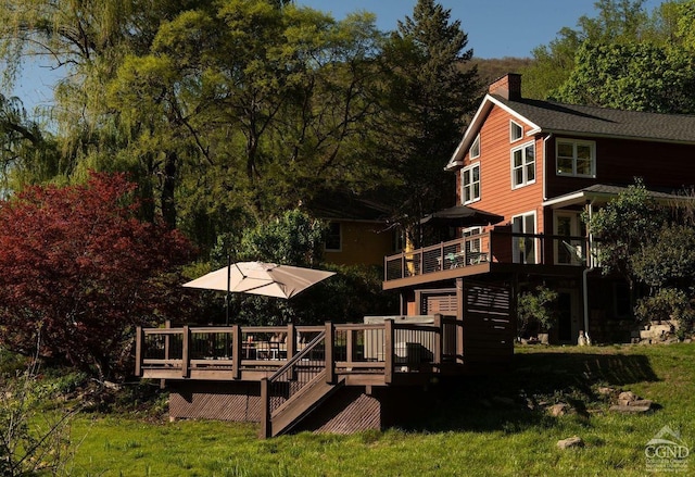 back of house with a chimney, a deck, and a yard