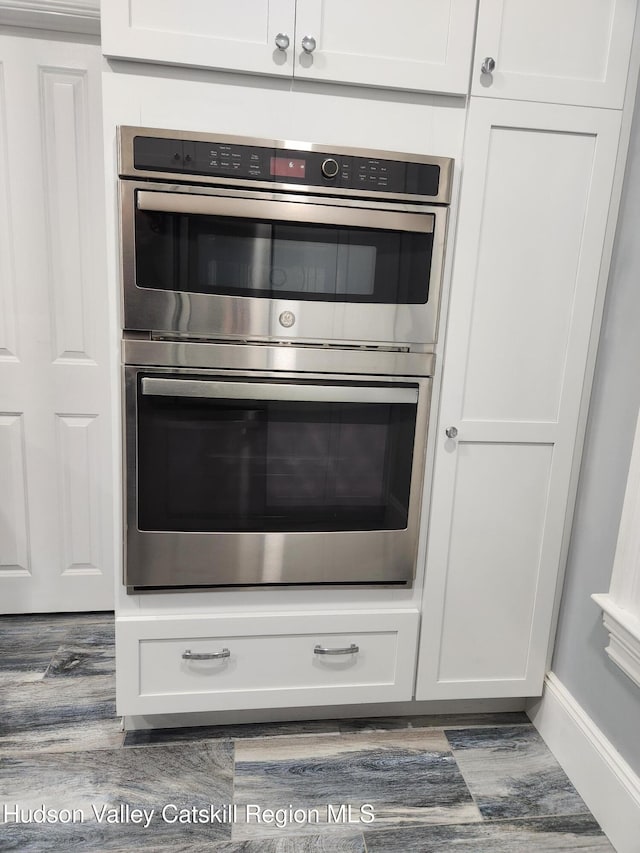 details with white cabinetry, wood finished floors, and stainless steel double oven