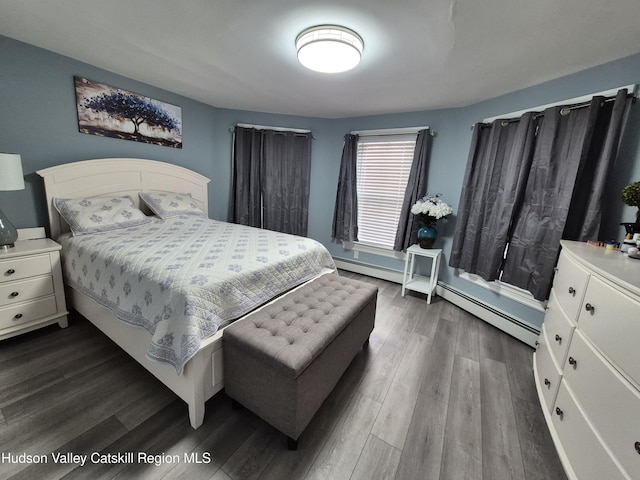 bedroom with a baseboard heating unit and dark wood-style flooring