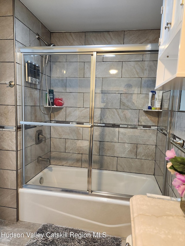 bathroom with bath / shower combo with glass door