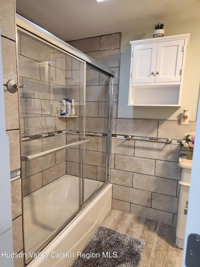 bathroom with wood finished floors and shower / bath combination with glass door