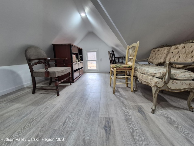 living area featuring baseboards, lofted ceiling, and wood finished floors