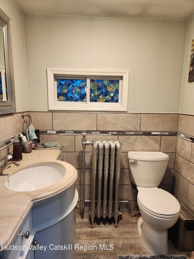 bathroom with toilet, tile walls, radiator, and vanity