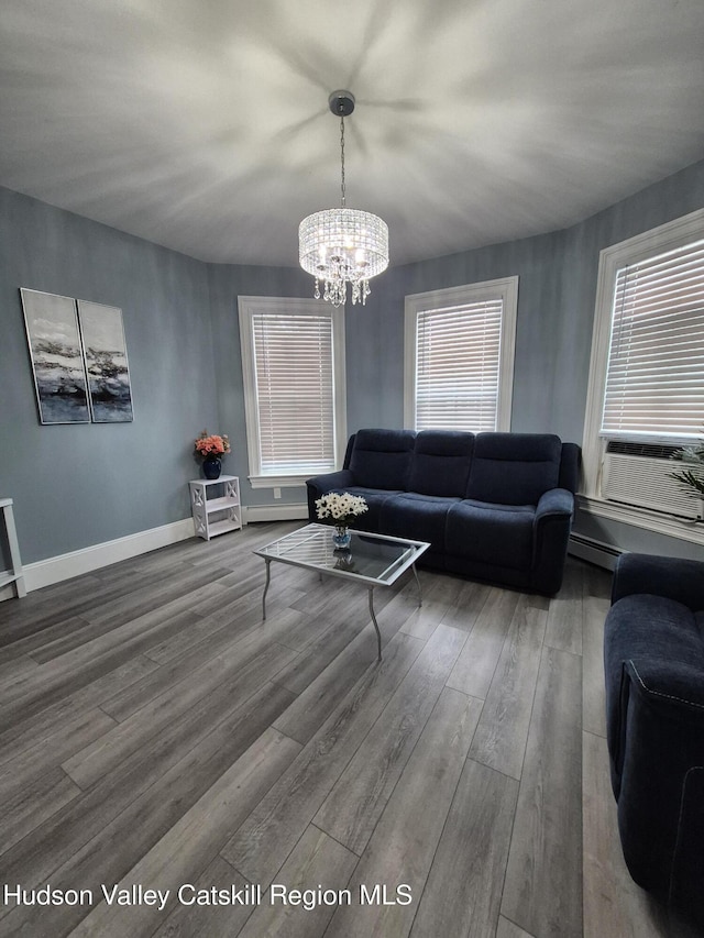 living area featuring an inviting chandelier, cooling unit, baseboards, and wood finished floors