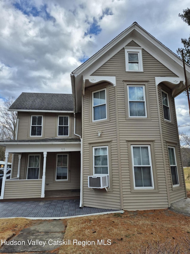 view of front of house with cooling unit, roof with shingles, and a porch