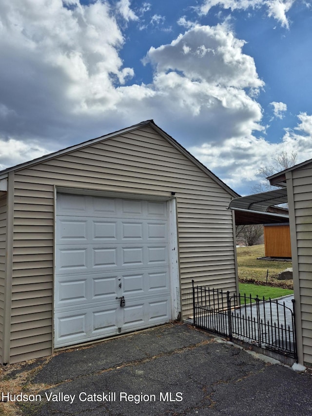 garage with aphalt driveway and fence