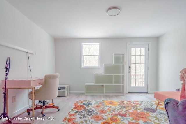 home office with a wall mounted air conditioner, plenty of natural light, baseboards, and wood finished floors