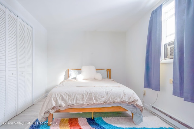 bedroom with cooling unit, baseboard heating, and wood finished floors