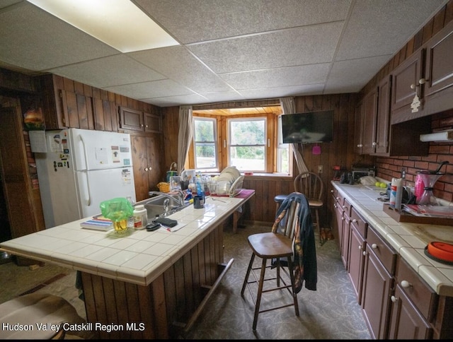 125 County Route 26a, Stuyvesant, NY 12106 - kitchen with tile counters, freestanding refrigerator, a drop ceiling, and wooden walls