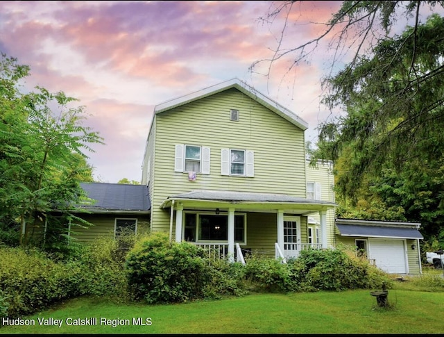 view of front facade featuring a lawn, covered porch, and a garage