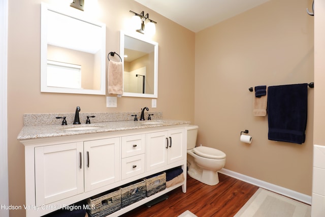 bathroom featuring toilet, wood finished floors, a sink, and baseboards