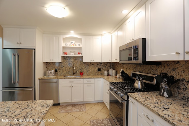 kitchen with white cabinetry, open shelves, appliances with stainless steel finishes, light tile patterned flooring, and a sink