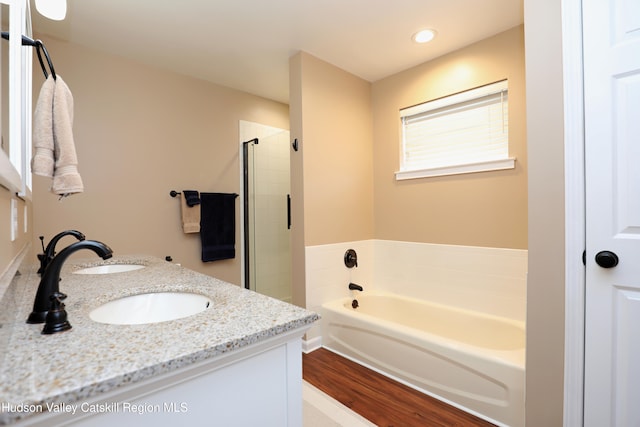full bathroom with a bath, a sink, recessed lighting, a shower stall, and wood finished floors