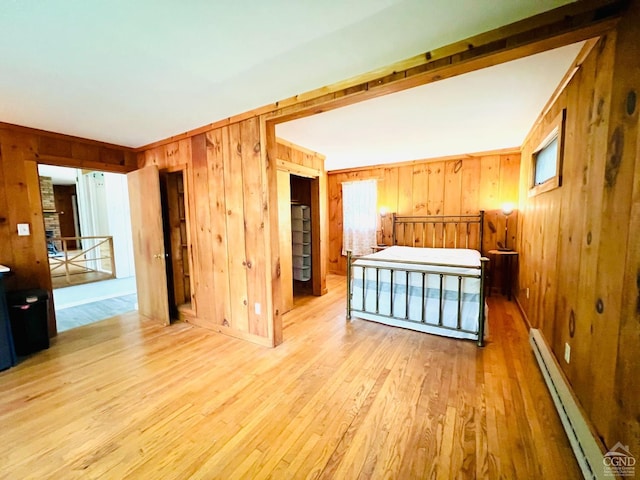 32 Harvey Mountain Rd, Austerlitz, NY 12017 - unfurnished bedroom with baseboard heating, wooden walls, and light wood-style flooring