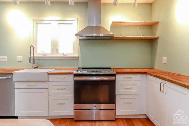 32 Harvey Mountain Rd, Austerlitz, NY 12017 - kitchen featuring stainless steel appliances, wall chimney range hood, a sink, butcher block counters, and white cabinetry
