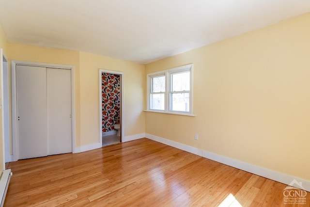 32 Harvey Mountain Rd, Austerlitz, NY 12017 - unfurnished bedroom featuring light wood-type flooring, baseboards, a baseboard radiator, a closet, and connected bathroom