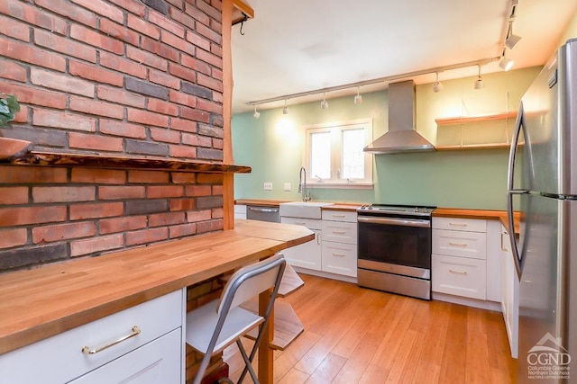 32 Harvey Mountain Rd, Austerlitz, NY 12017 - kitchen with appliances with stainless steel finishes, wall chimney exhaust hood, rail lighting, a sink, and wooden counters