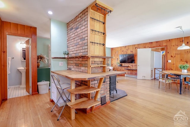 32 Harvey Mountain Rd, Austerlitz, NY 12017 - kitchen with wood walls, light wood-type flooring, baseboard heating, a wood stove, and hanging light fixtures