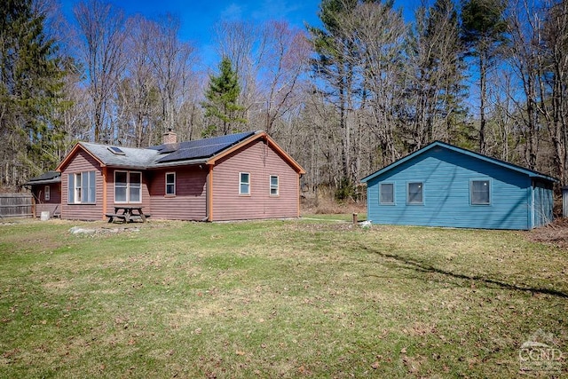 32 Harvey Mountain Rd, Austerlitz, NY 12017 - back of house featuring roof mounted solar panels, a chimney, and a lawn
