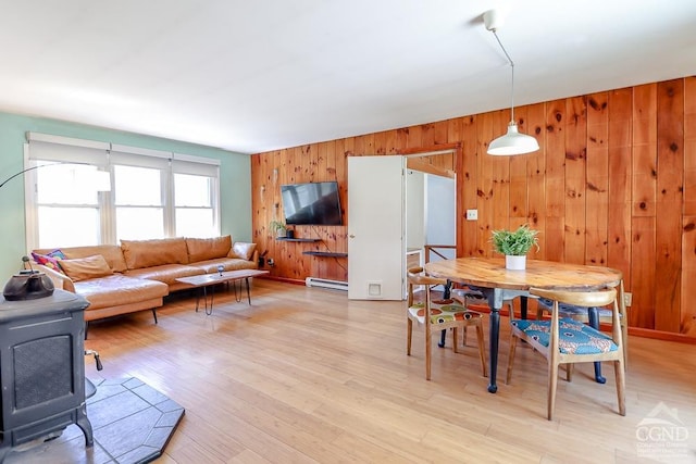 32 Harvey Mountain Rd, Austerlitz, NY 12017 - dining room featuring wood walls, a baseboard radiator, a wood stove, and light wood-type flooring
