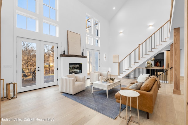 living room featuring french doors, light hardwood / wood-style flooring, and high vaulted ceiling