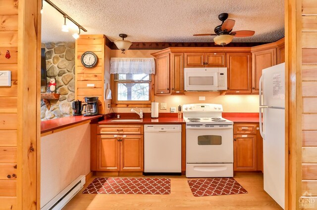kitchen featuring white appliances, a sink, light wood-style floors, a ceiling fan, and a baseboard radiator