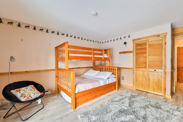 bedroom featuring wood finished floors, a closet, and a baseboard heating unit