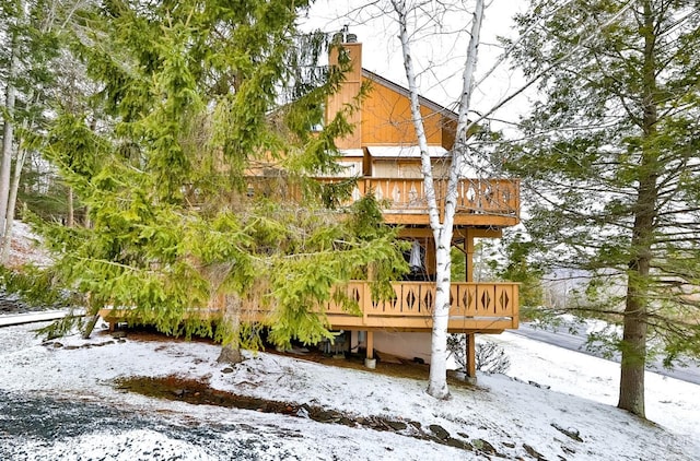 snow covered property featuring a wooden deck and a chimney