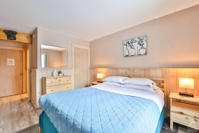 bedroom with wooden walls, wood finished floors, and a closet