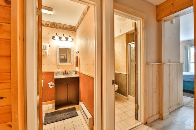 full bath with a baseboard radiator, wainscoting, a shower stall, toilet, and vanity