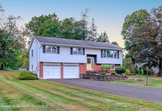 bi-level home featuring a garage and a yard