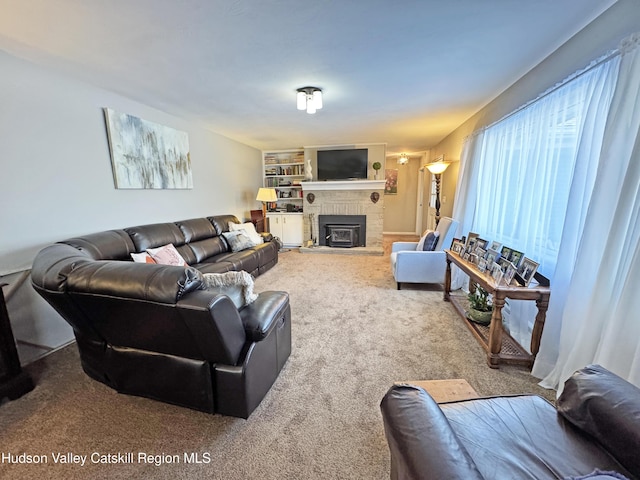 carpeted living room featuring a brick fireplace and built in shelves